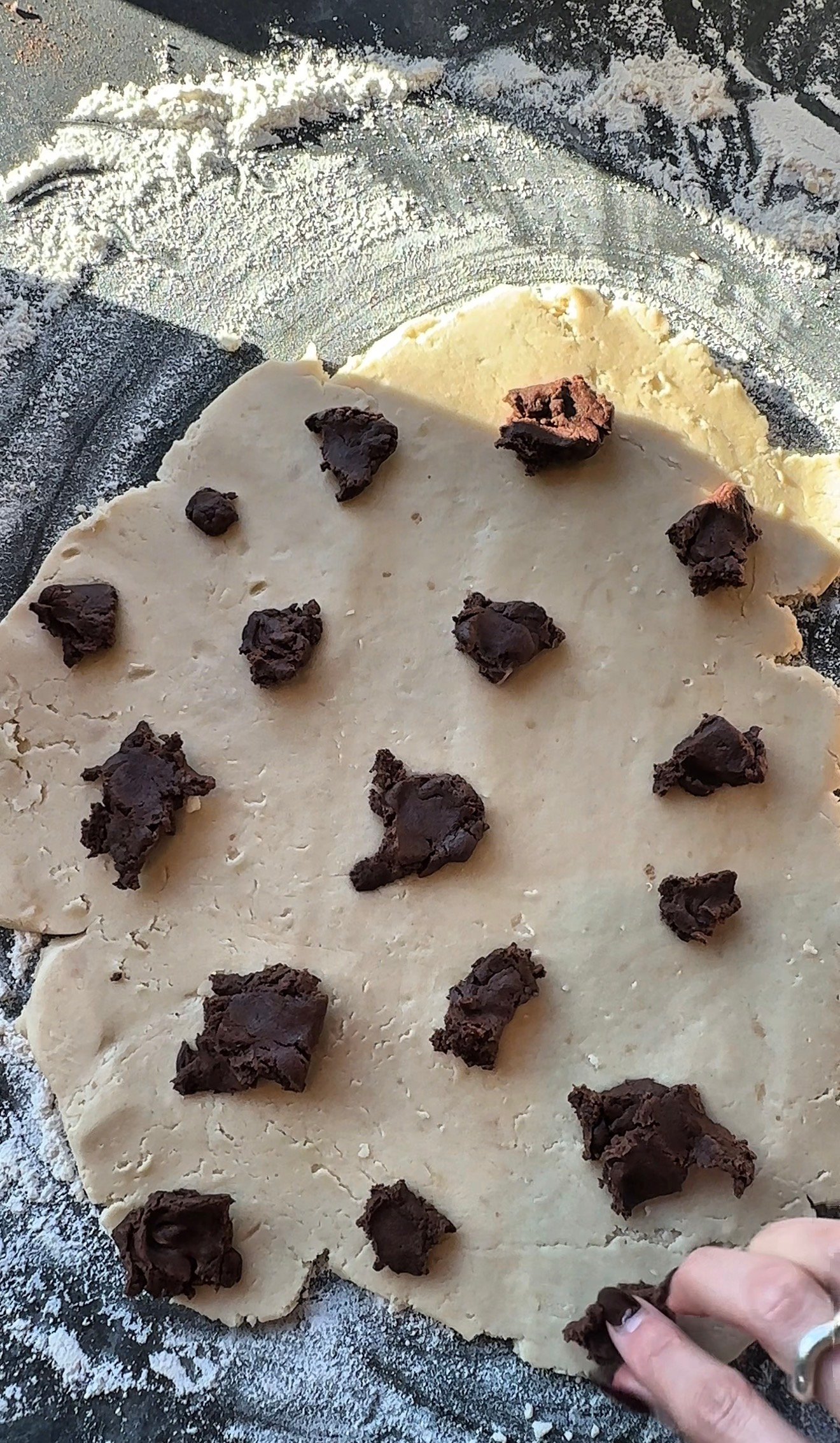 Chocolate brown dough pieces pressed into vanilla dough to create cow spot pattern for Christmas cookies