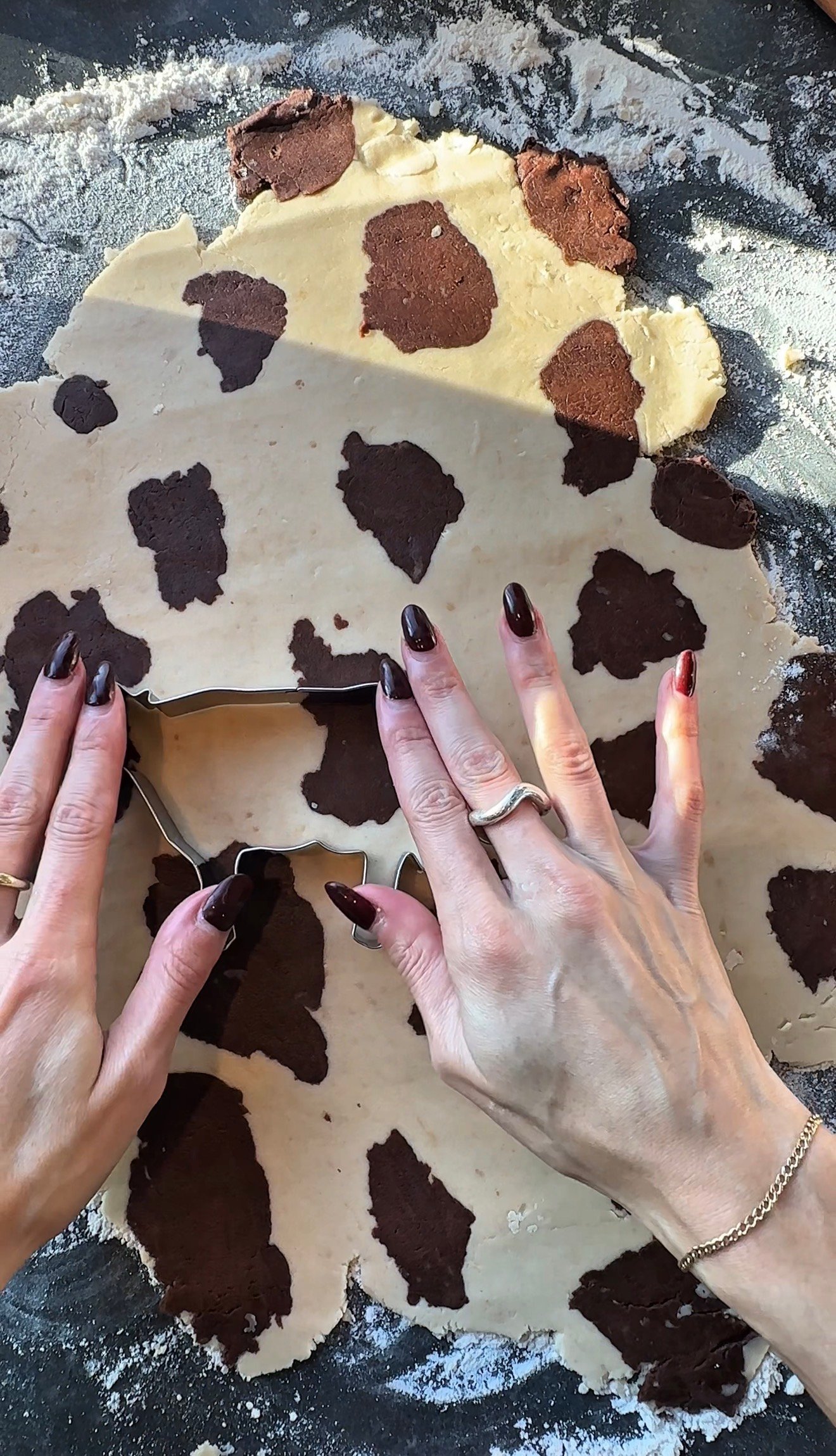 Chocolate brown dough pieces pressed into vanilla dough to create cow spot pattern for Christmas cookies