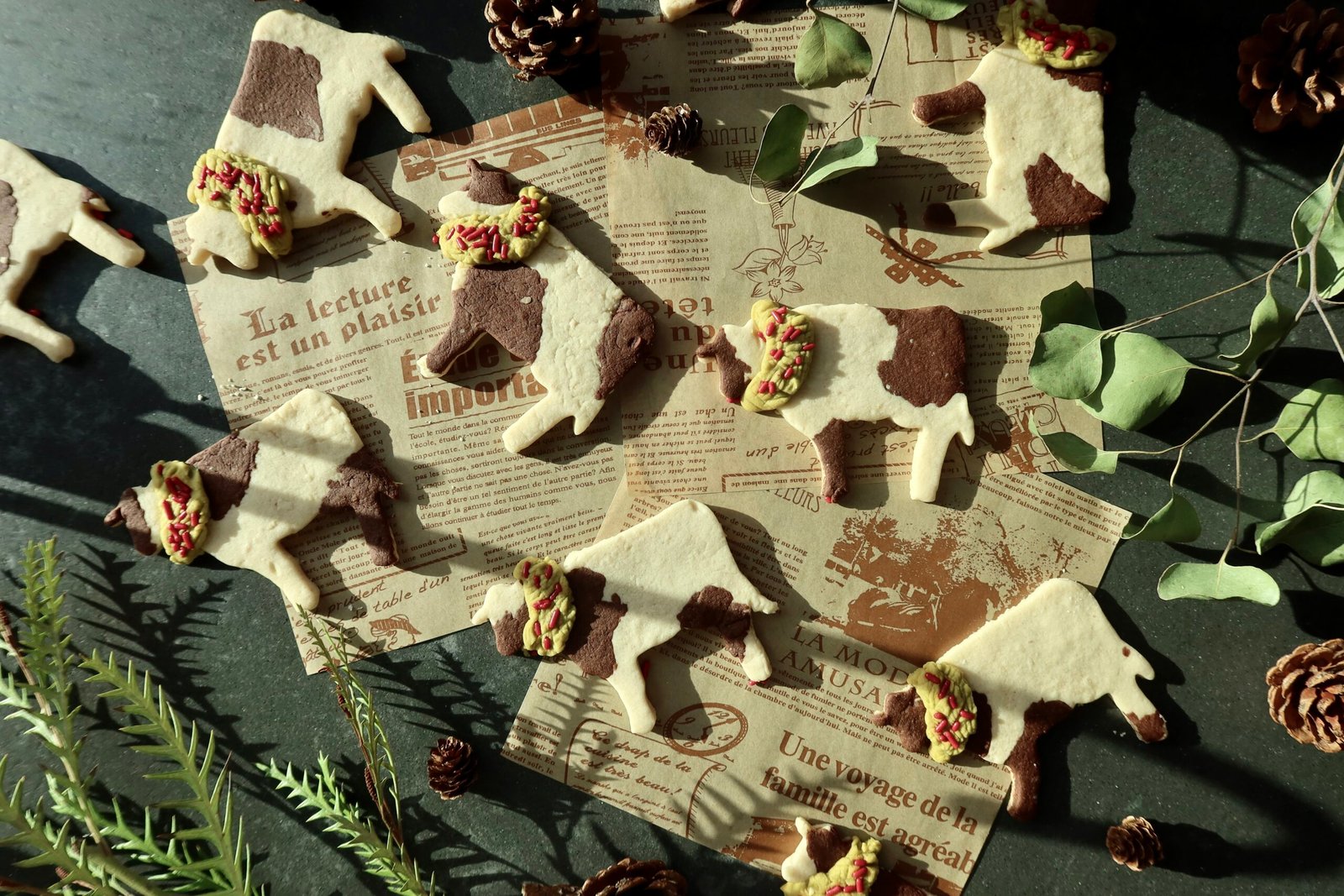 Christmas cow cookies with marbled cow spots green wreath collars and red sprinkles