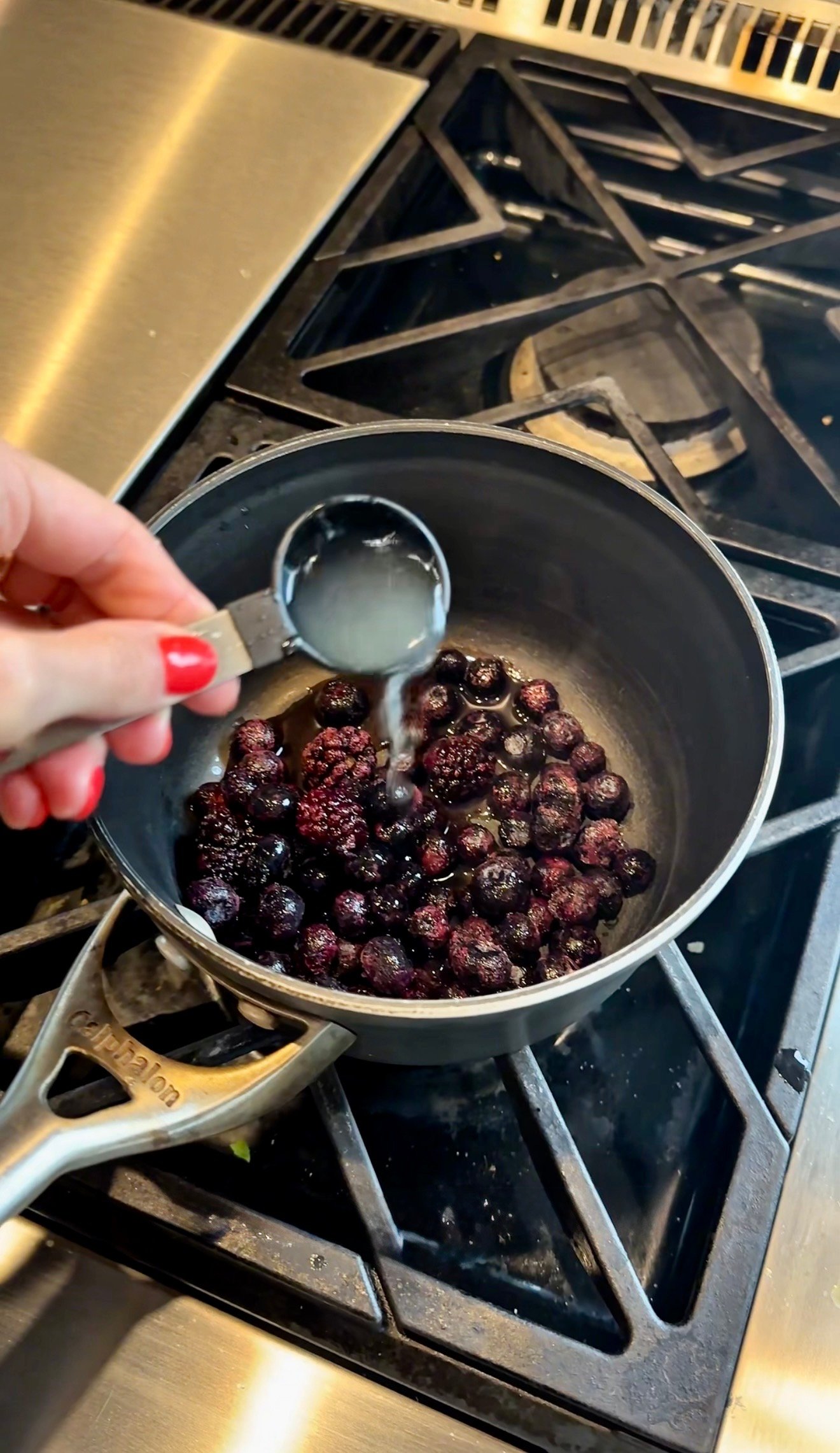 Blueberry compote simmering in a saucepan with maple syrup vanilla and lemon zest