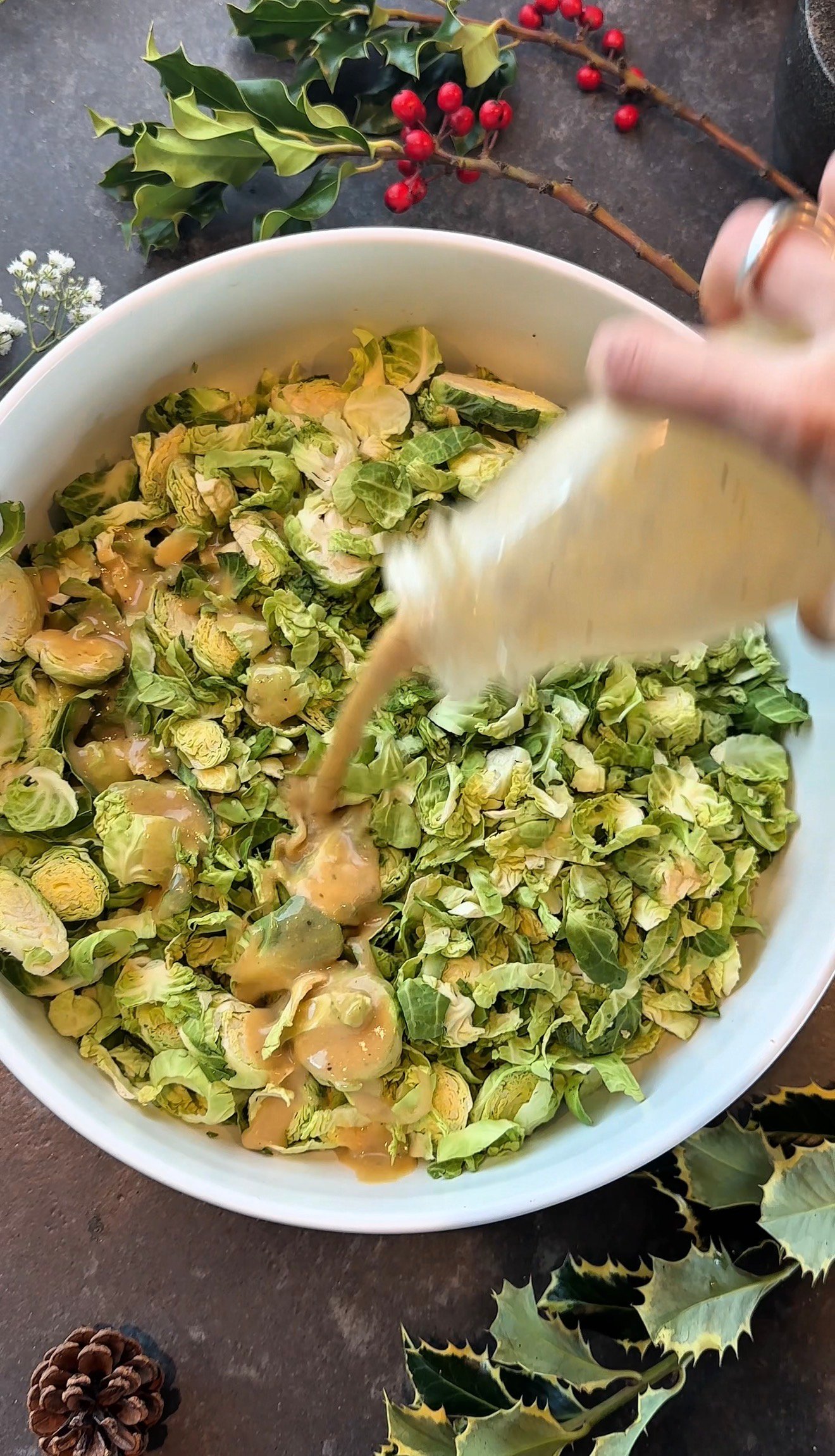 Miso parmesan vinaigrette being poured over winter shaved Brussels sprouts salad
