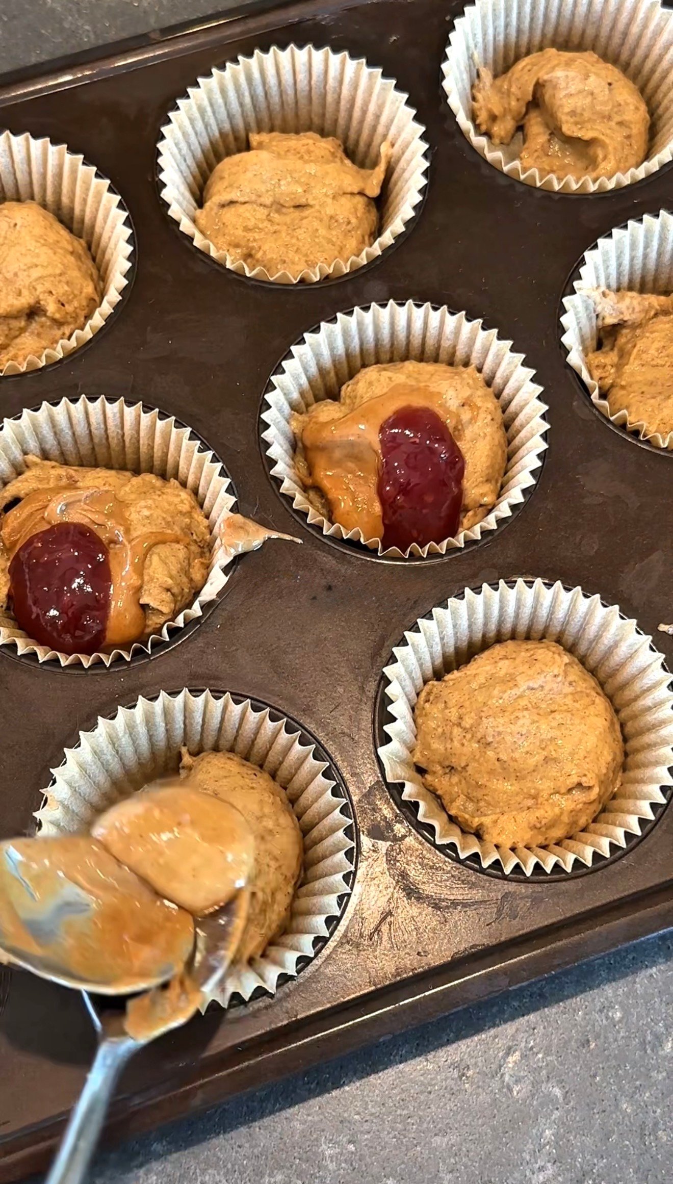 Adding peanut butter and jam center to high protein breakfast muffin cups before baking