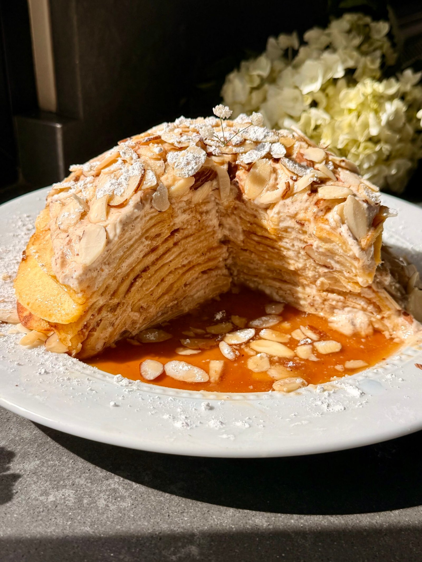 High protein almond croissant crepe stack layered with almond cream and topped with sliced almonds and powdered sugar