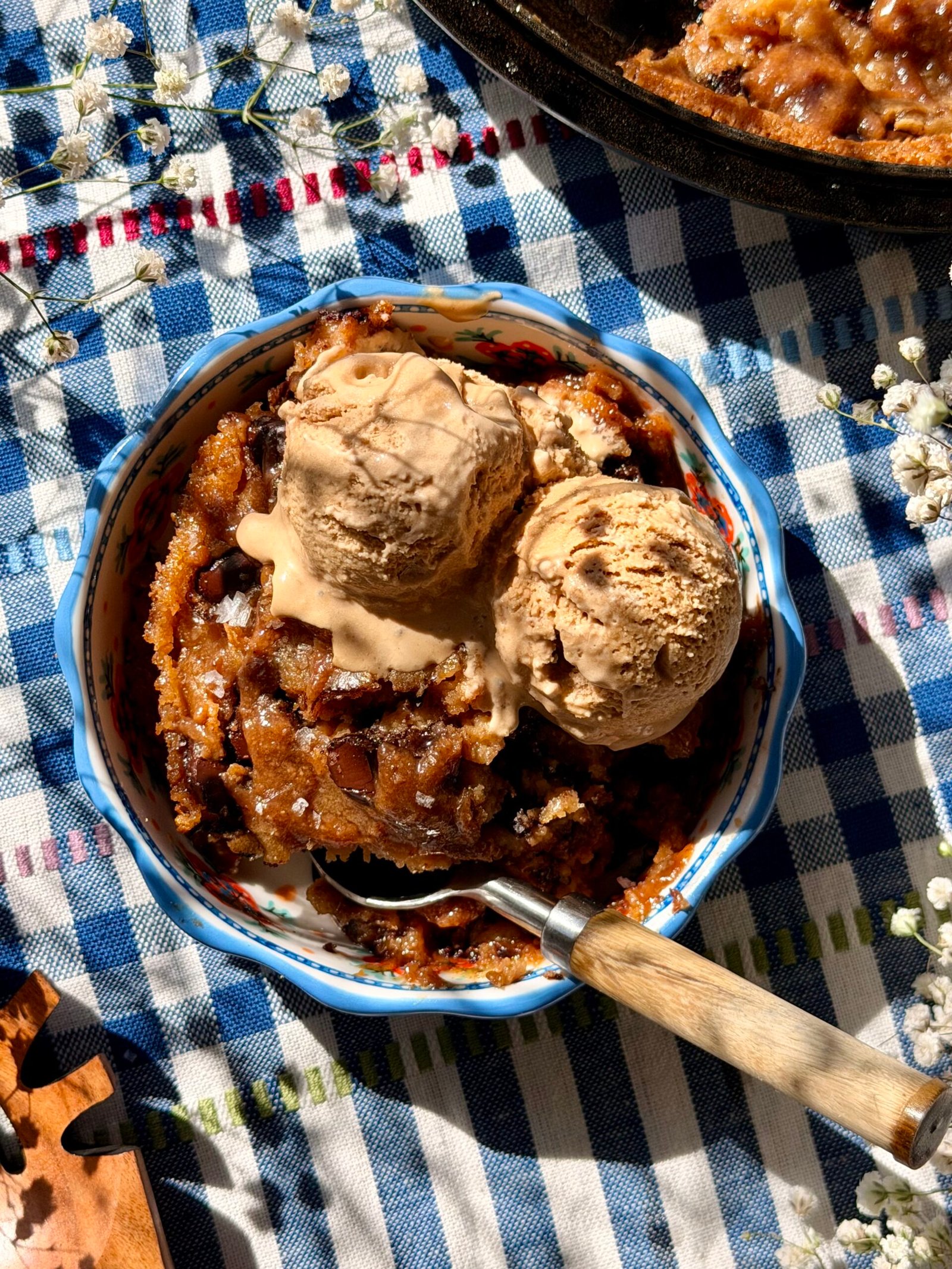 Brown butter miso chocolate chip skillet cookie in a cast iron skillet with maple miso drizzle and flaky sea salt